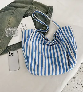 Flat lay of large blue striped canvas tote bag with books and denim jacket