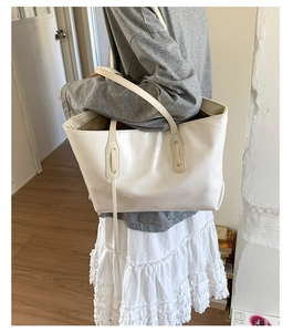 Detailed close-up of a white faux leather tote bag with crocodile pattern texture