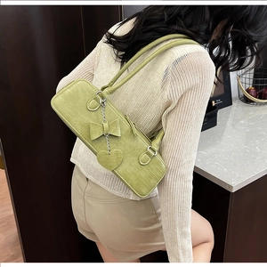 Détail du sac bandoulière vert fruit effet croco avec nœud et pendentif en forme de cœur