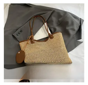 Detailed texture of woven straw tote bag with brown leather straps on a minimalist setting