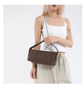 Detail of brown matte canvas handbag with decorative stitching and metal chain strap