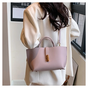 Detail of light purple lychee texture tote bag with golden twist lock on white blazer