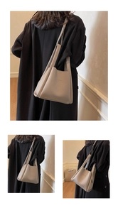 Detail view of beige pebbled leather bucket bag with embossed logo and shoulder strap