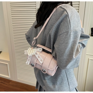 Vista dettagliata di una borsa a cilindro rosa con un grande fiocco di pizzo e perle