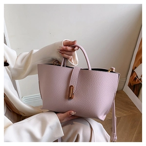 Close-up of lavender lychee leather tote bag with golden metal twist lock and handle
