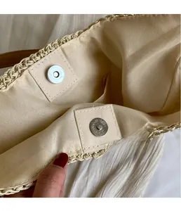 Detail of woven straw bag interior featuring secure silver magnetic snap closure and lining