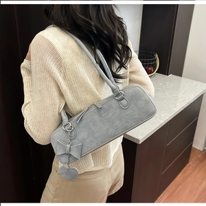 Sac bandoulière gris texture crocodile avec breloques cœur porté par un mannequin