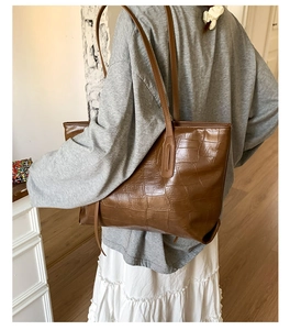 Brown crocodile embossed tote bag shown on model highlighting large capacity and texture