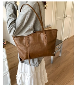Detail shot of large brown crocodile pattern tote bag with slender shoulder strap