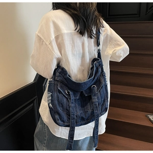 Detail of vintage denim crossbody bag featuring distressed finish and metal ring straps