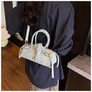 Detail of light blue denim pillow bag with rivet bow and silver hardware strap