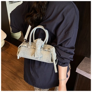 Detail of light blue denim bow handbag with silver hardware and detachable long strap