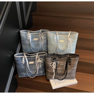 Dettaglio borse tote in denim con ciondoli a fiocco di perle e manici in pelle lucida