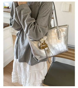 Detail of silver crocodile embossed tote bag with a cute plush bear charm accessory