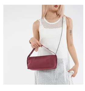Detail of burgundy cylinder shoulder bag with chain strap on white crochet dress