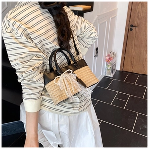 Straw tote bag with black leather trim and lace pearl bow detail on a female model