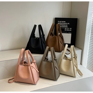 Five minimalist pebbled leather bucket bags in pink, grey, white, black, and brown