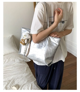 Silver crocodile embossed tote bag with a cute bear charm shown in a daily lifestyle scene