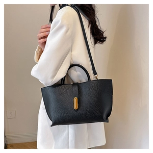 Detail of black lychee grain leather tote bag with gold oval twist lock and shoulder strap