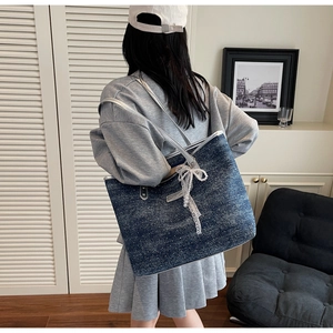 Detail of dark blue denim tote bag with shiny polka dots and lace pearl bow charm