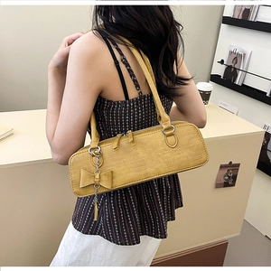 Détail du sac porté épaule jaune à texture crocodile avec pendentif nœud élégant
