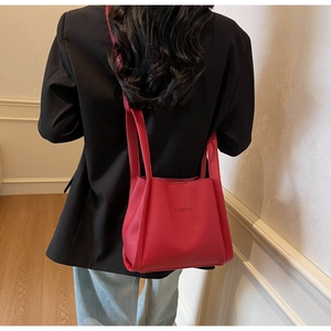 Detailed view of red pebble leather bucket bag featuring embossed logo and shoulder strap