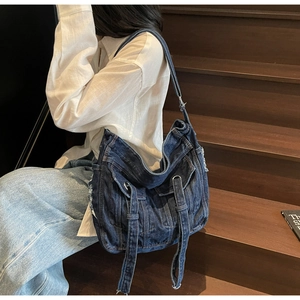 Detailed close-up of large blue denim bucket bag with decorative jeans-style pockets