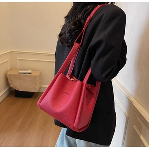 Detail of red lychee grain leather bucket bag featuring debossed BALIROC logo