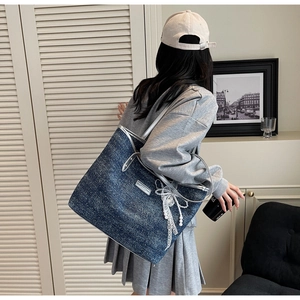 Detail of blue denim tote bag with silver leather trim and white lace pearl bow
