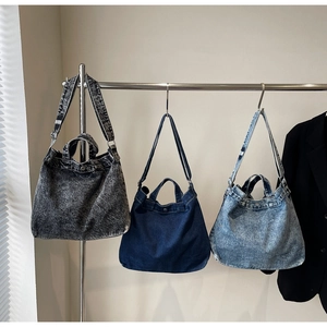 Three retro denim tote bags in dark grey, deep blue, and light blue shown on a rack