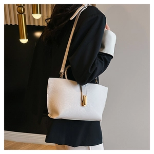 Detail of white lychee leather tote bag with gold metal lock on a model shoulder