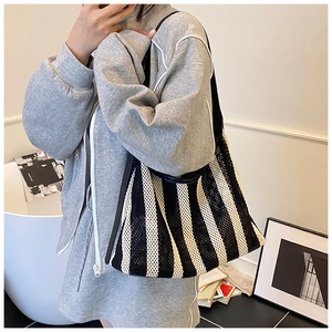 Gros plan d'un grand sac cabas en maille à rayures noires et blanches avec anses en cuir