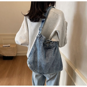 Dettaglio del tessuto in denim lavato azzurro con tracolla e fibbia regolabile