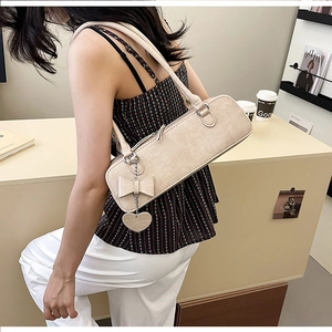 Détail du sac à bandoulière crème avec motif crocodile et breloque en forme de cœur