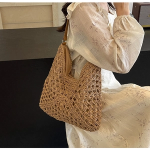 Close-up of handmade hollow crochet straw bag with brown leather strap and inner lining