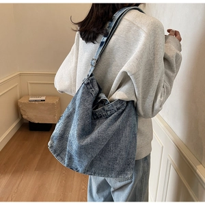 Detail of blue washed denim tote bag with adjustable strap shown on model shoulder