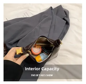 Internal capacity of the dark brown leather shoulder bag showing makeup items and gold buckle