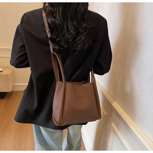 Brown lychee leather bucket bag showing adjustable shoulder strap on female model