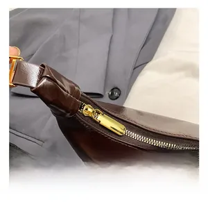 Close-up of golden zipper and shiny dark brown oil wax leather on minimalist bag