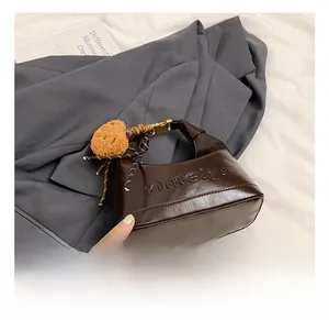 Close-up of deep brown glossy leather handbag with gold buckles and plush charm