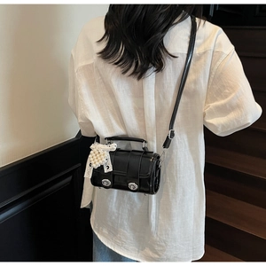 Borsa quadrata in vernice nera con ciondolo a cuore di perle indossata da modella