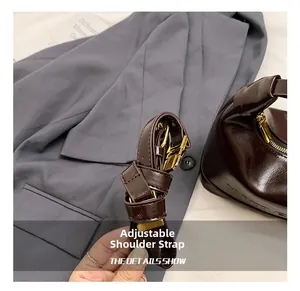 Detail of adjustable dark brown oil wax leather shoulder strap with gold metal buckle