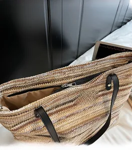 Detail of multi-color striped straw tote bag showing smooth metal zipper and woven texture