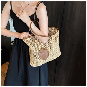 Detailed view of woven straw tote bag texture with brown leather straps and round trim