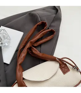 Dettaglio borsa a tracolla intrecciata crema con cinturino in pelle marrone su blazer grigio