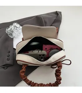Vista interna della borsa a tracolla beige con tasca con zip e oggetti quotidiani