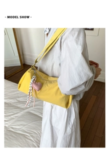 Detail of yellow nylon pillow bag with heart pendant and knot tassel in lifestyle setting