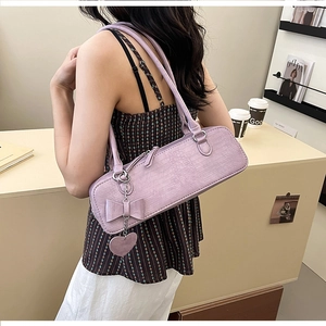 Détail du sac baguette lilas avec texture crocodile et breloque en forme de cœur nceud
