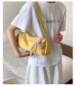 Detail of yellow canvas barrel bag with pink heart charm and striped rope decoration