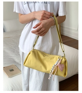 Détail du sac polochon en toile jaune avec breloque cœur rose et fermeture éclair argentée